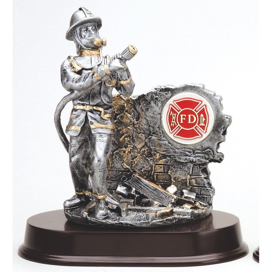 Silver fireman statue with gold trim, holding a hose, next to a rubble wall with a red FD logo, on a dark cherry-finish base.