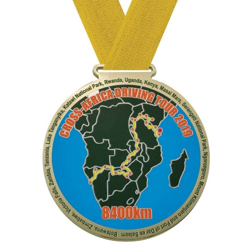 Gold Olympic medal with a custom "Cross-Africa Driving Tour 2019" map design and yellow ribbon.
