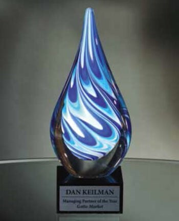 Blue and white swirled art glass teardrop award on a black glass base with engraved plaque.