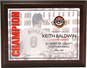 Dark wood plaque with "Champion" in red, featuring a baseball player and Cal Ripken Baseball logo.