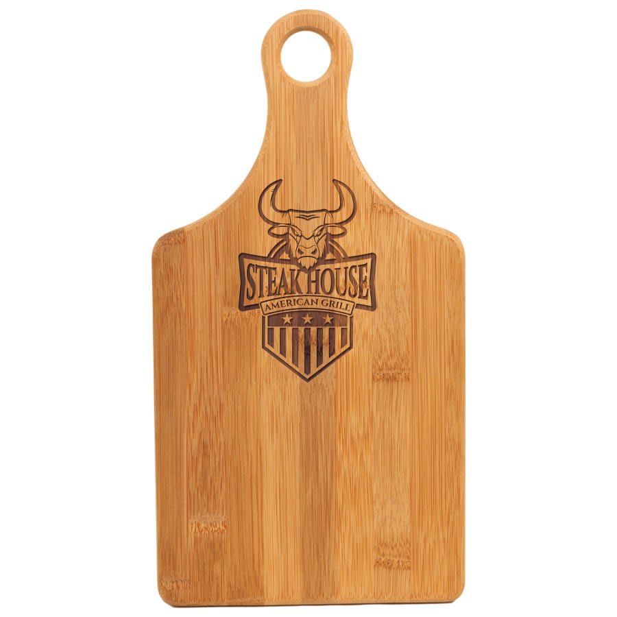 Light brown bamboo paddle-shaped cutting board with a handle and "Steak House American Grill" laser engraving.