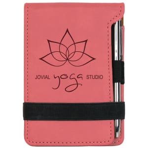 Pink laserable leatherette mini notepad with "Jovial Yoga Studio" logo, pen, and elastic band.