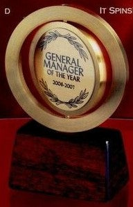 Brass spinner award with "General Manager of the Year" engraved disk on a dark rosewood base.