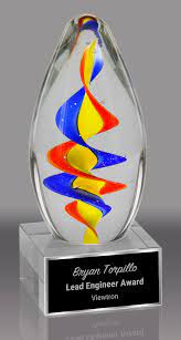 Clear art glass egg with rainbow spiral, on a clear glass base with an engraved black plate.