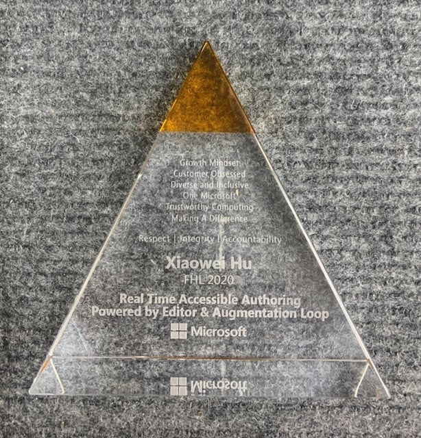 Clear crystal pyramid award with a gold top, engraved with text and Microsoft logos.