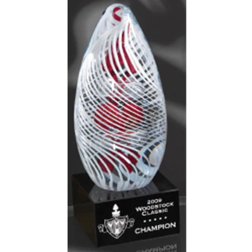 Clear art glass egg with red shapes and white swirls on a black base.