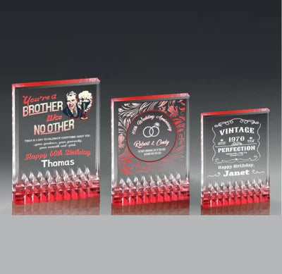 Three clear acrylic awards with red jewel-cut bases and personalized engravings.
