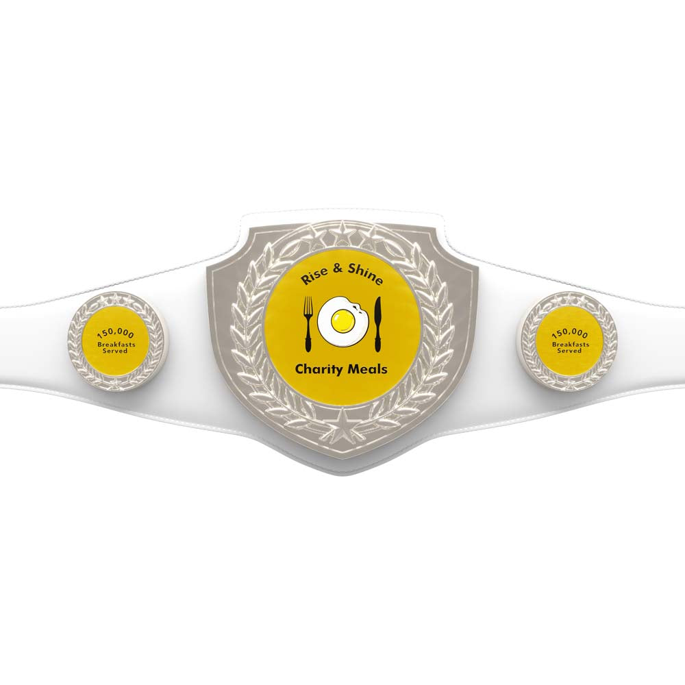 White vegan leather championship belt with "Rise & Shine Charity Meals" and a fried egg on the main plate, flanked by two "150,000 Breakfasts Served" side plates.