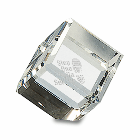 Clear crystal cube paperweight with beveled corners, engraved with "Step One Media Service" and a footprint logo.